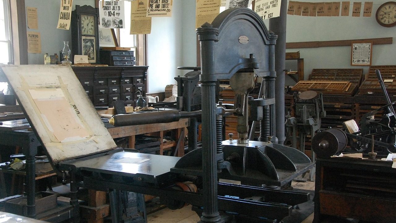 Newspapers and press materials spread across a surface in a busy newsroom.