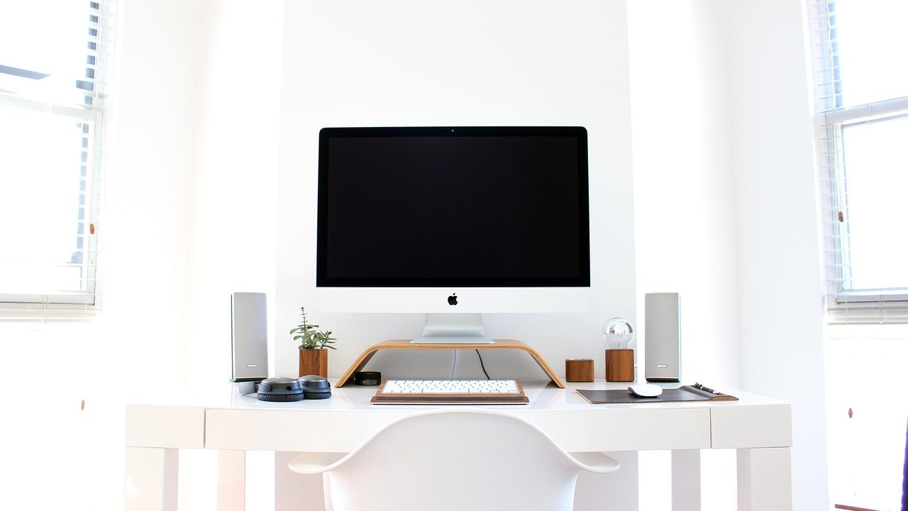 A vacant desk with a dark monitor and keyboard in a dimly lit office.