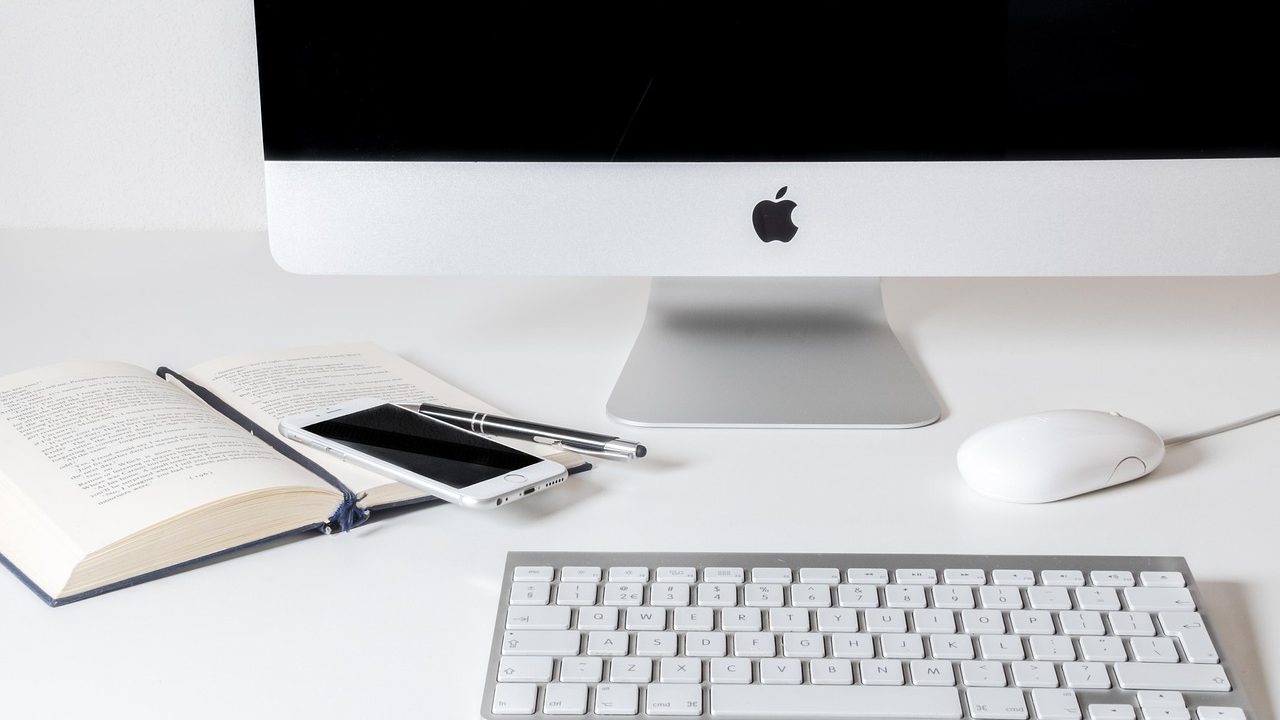 A MacBook displaying terminal code on a developer workstation setup.