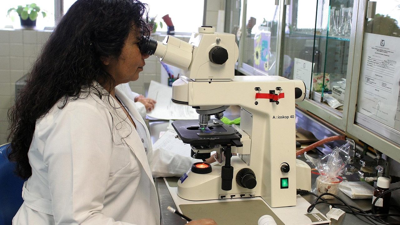 A scientist examining samples through a microscope in a research laboratory.