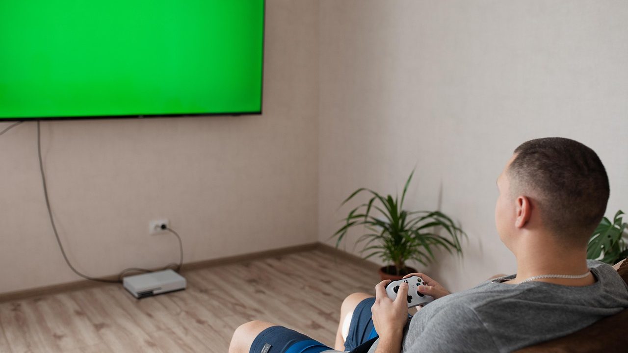 A gaming console and controller sitting in front of a large living room television.