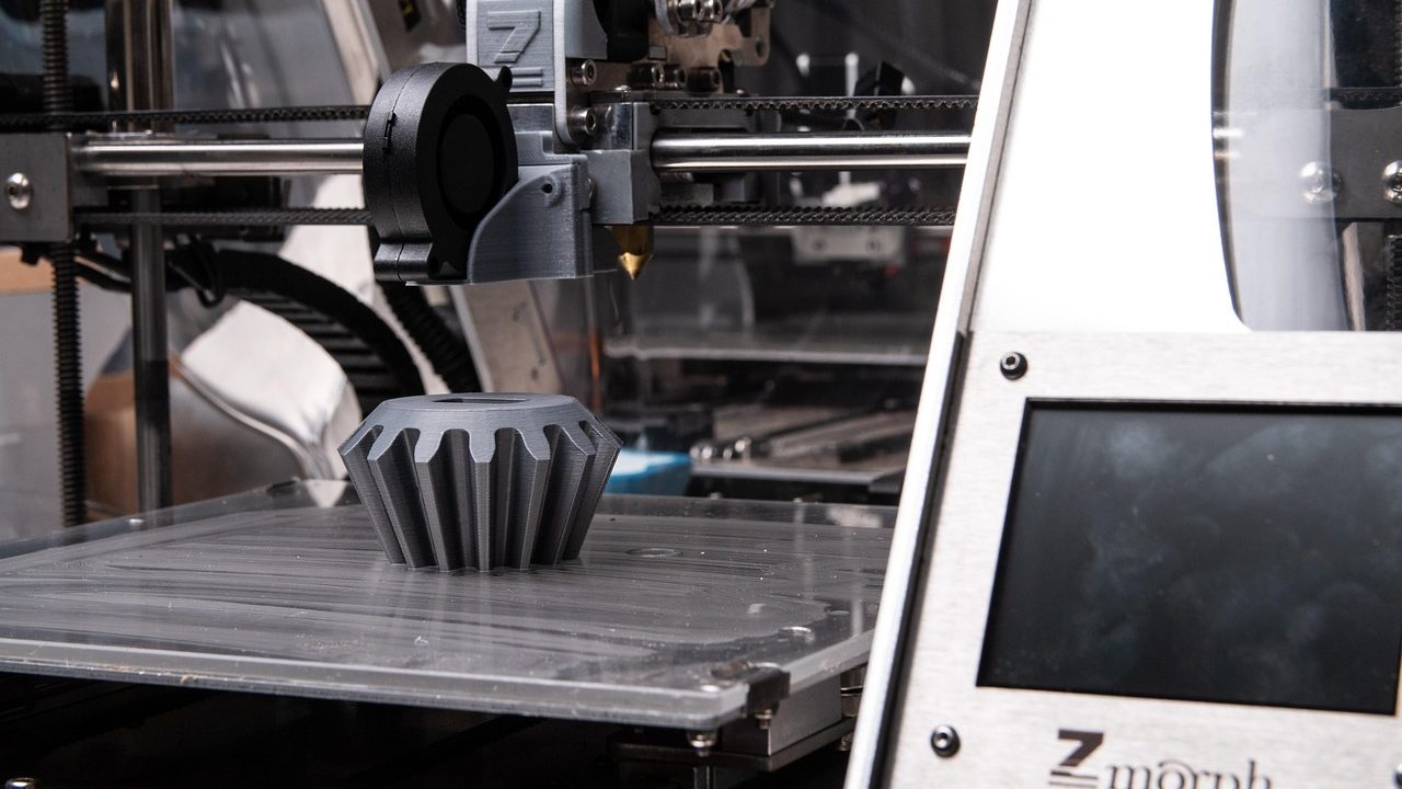 A desktop 3D printer extruding plastic filament to build a small object layer by layer.