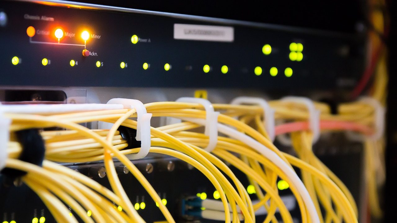 Rows of blinking server rack lights glow blue in a darkened data center corridor.