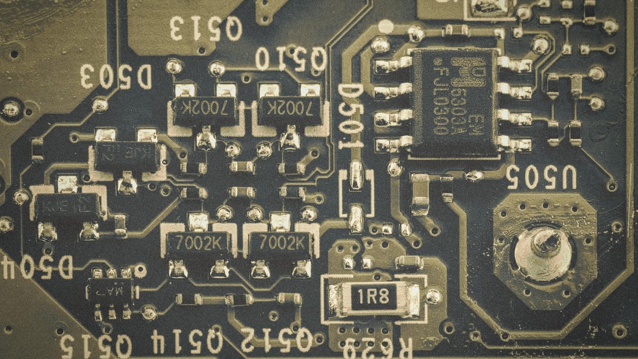 Close-up macro photograph of a vintage green circuit board with through-hole components.
