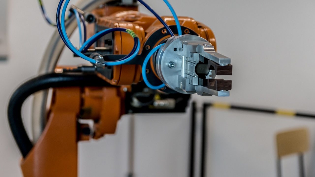 An articulated robotic arm on an automated manufacturing floor surrounded by industrial equipment.