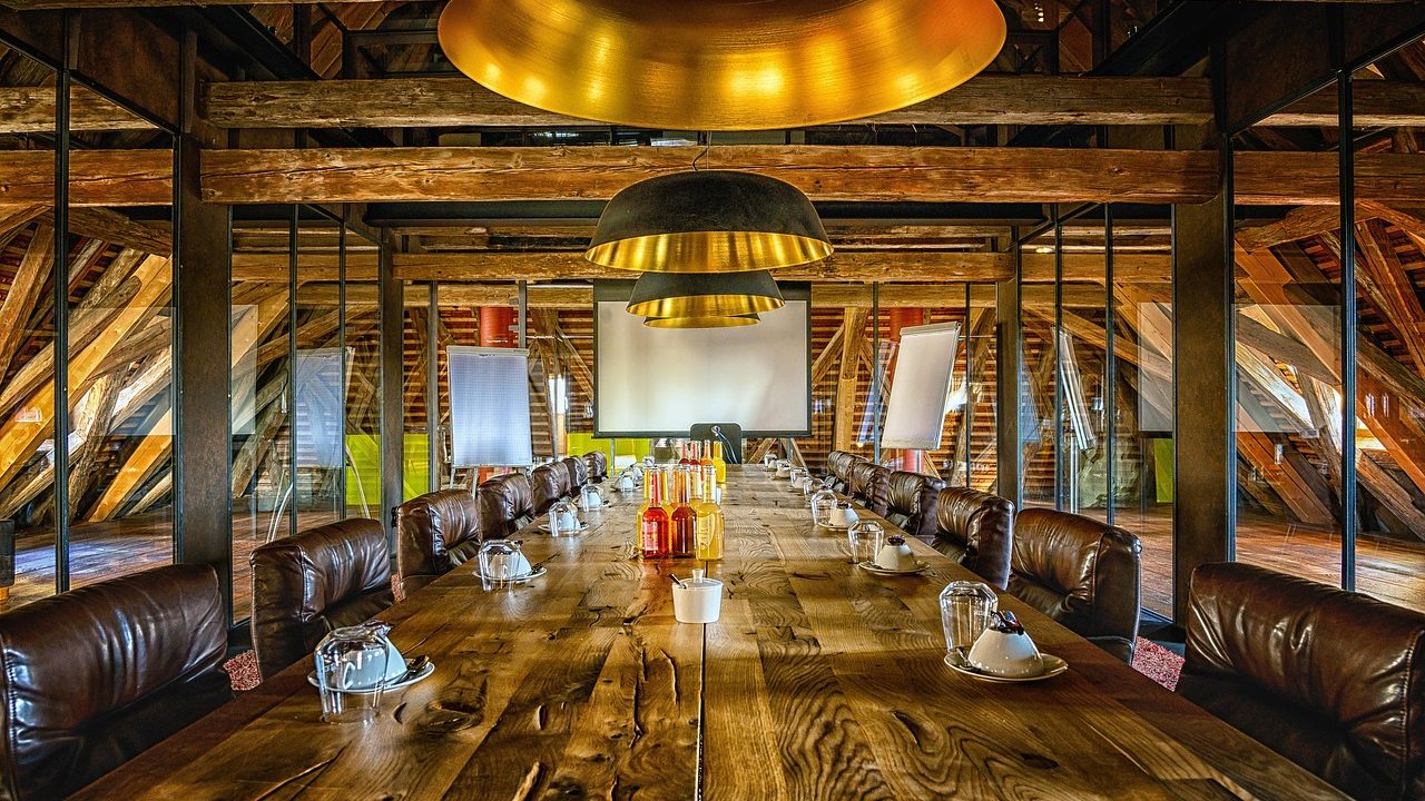 Empty conference room with chairs around a long table under fluorescent lights.