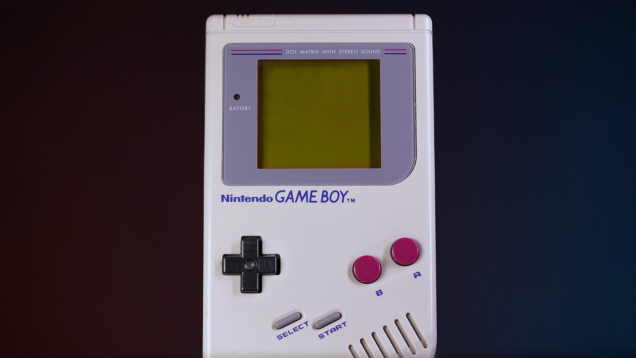 A vintage video game console and controller sitting on a wooden surface.