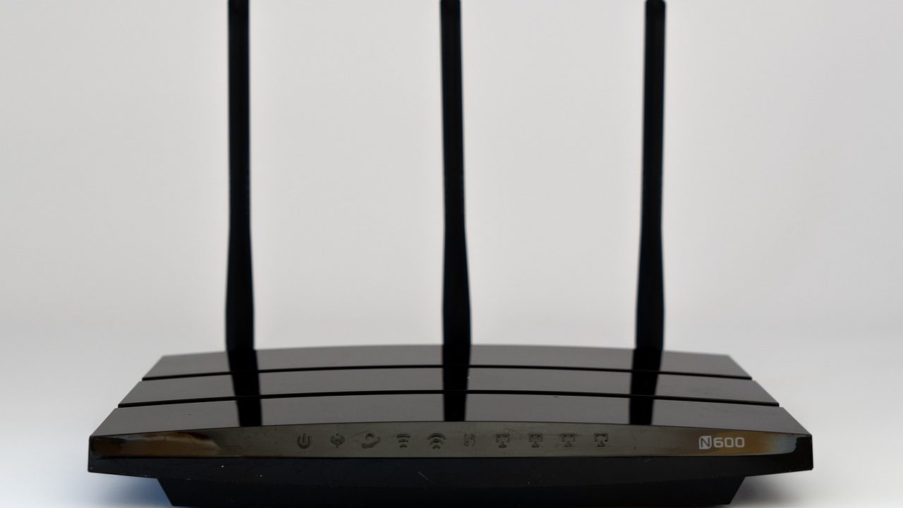 A consumer wireless router with indicator lights glowing on a desk.