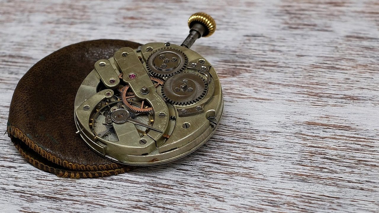 A watchmaker's hands using fine tools to assemble the movement of a mechanical timepiece.