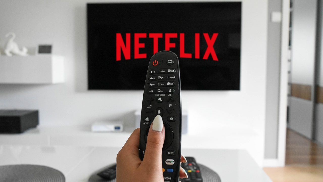 A small black streaming stick plugged into the HDMI port on the back of a flat-screen television.