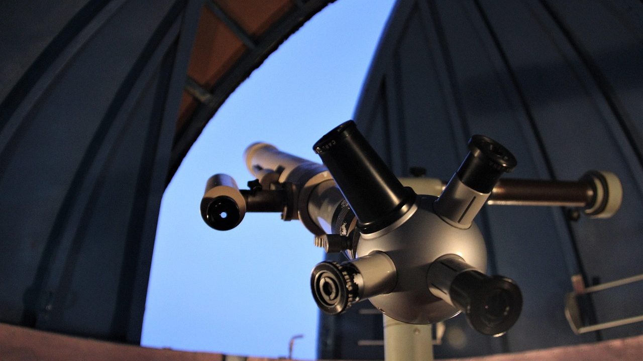 A large observatory dome open to the sky on a mountain summit at sunset.