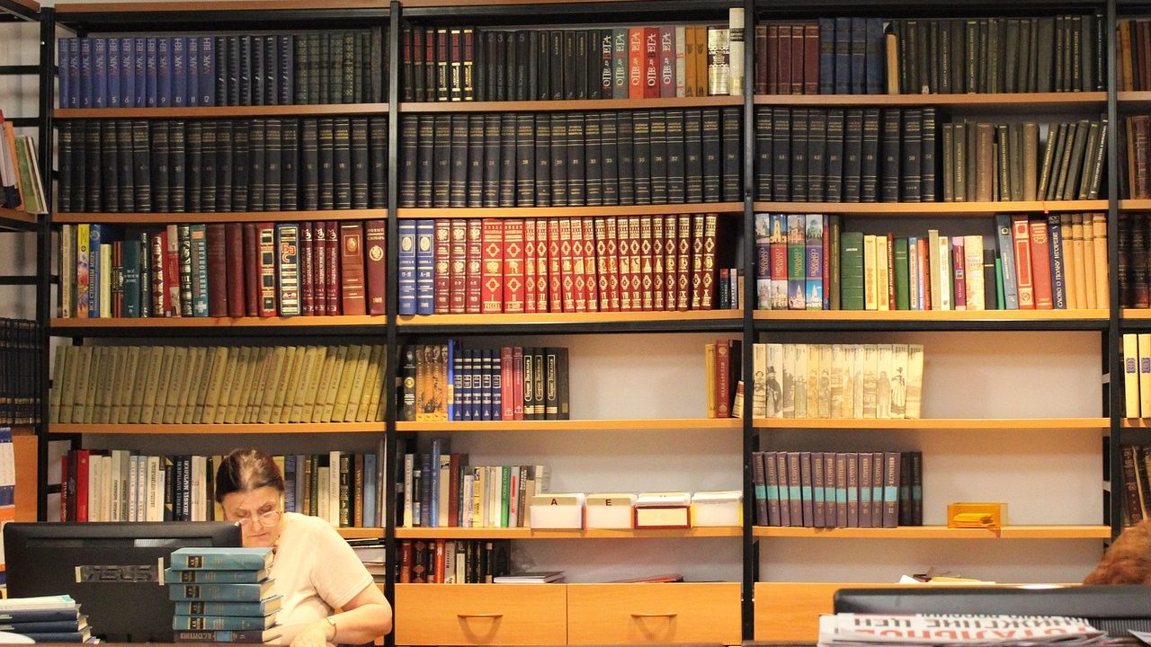 Long rows of archival document shelves inside a dimly lit library storage room.