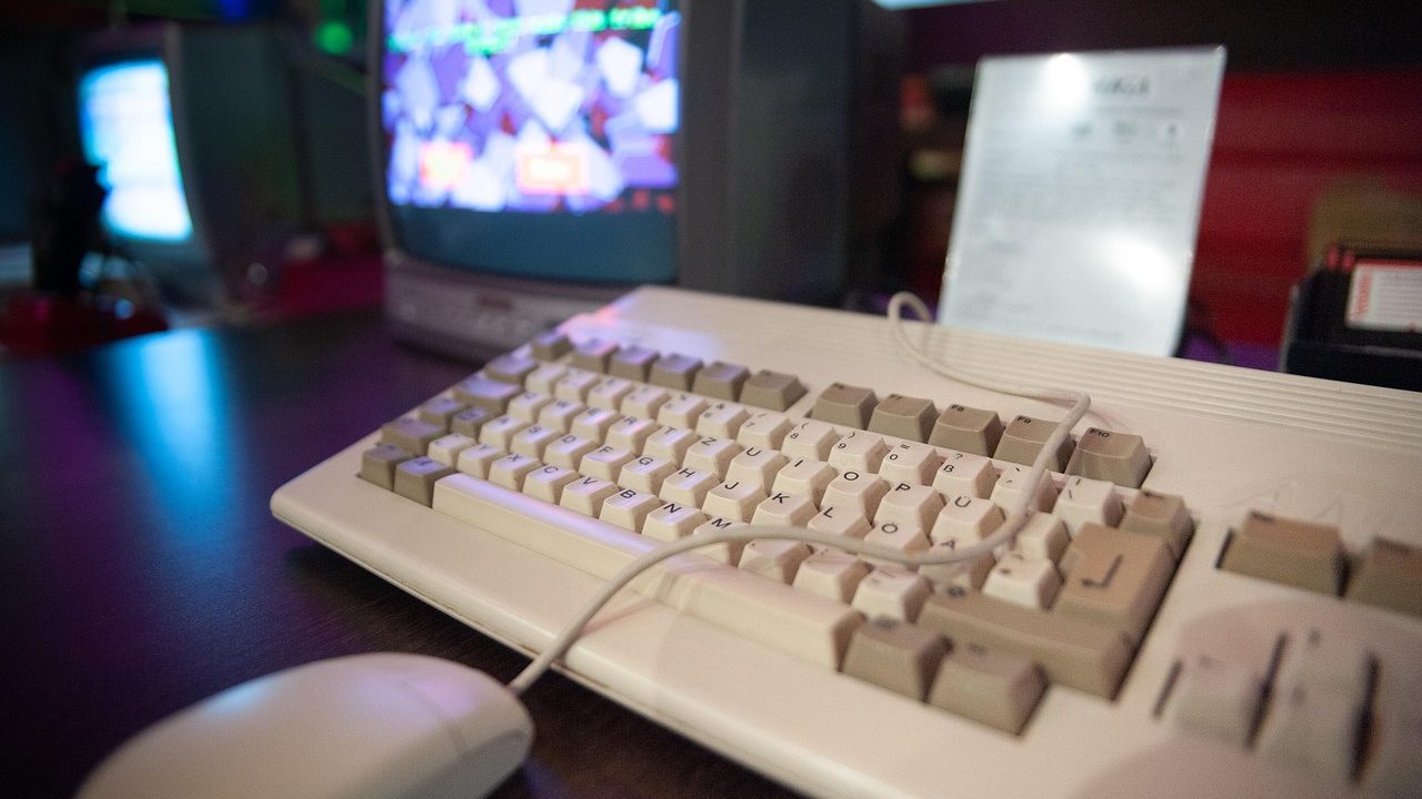 Close-up of an aged mechanical keyboard with cream-colored keycaps on a wooden desk.