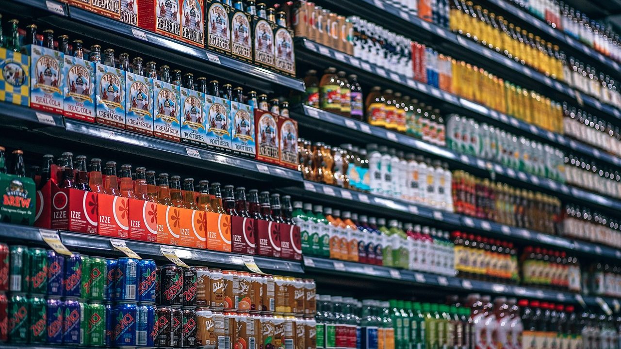Rows of canned sardine tins stacked on a grocery store shelf under fluorescent lighting.