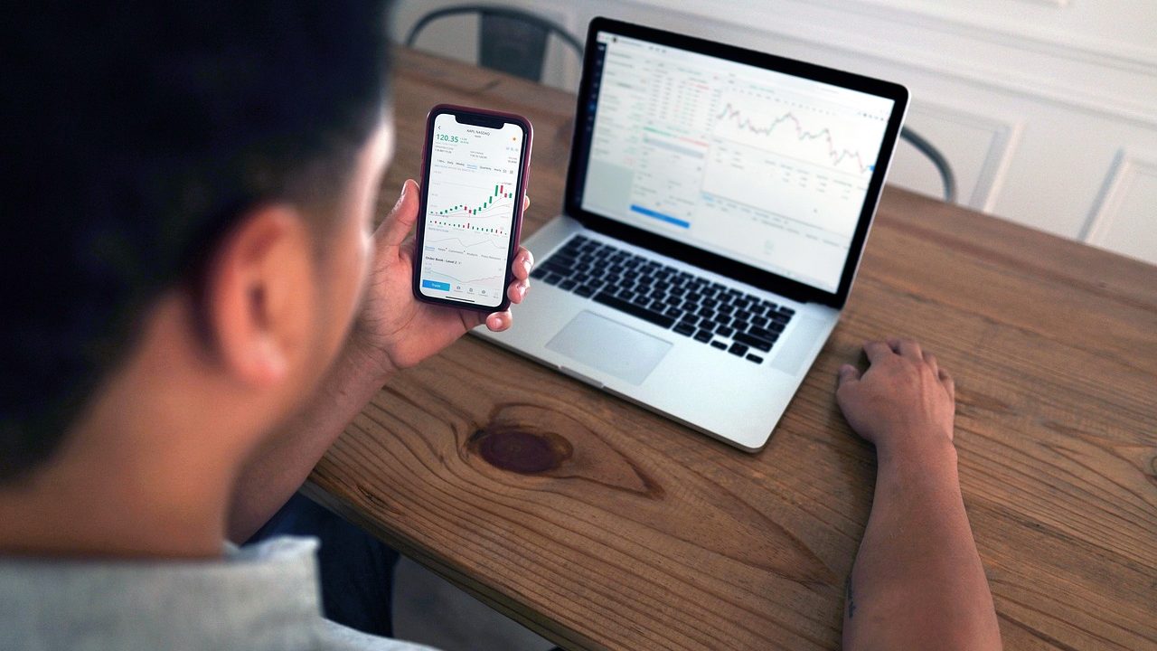 A busy trading floor with multiple screens displaying financial data and traders at workstations.