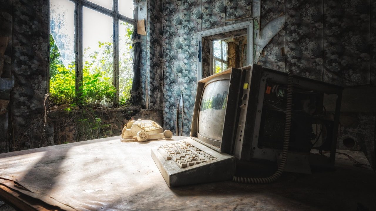 An old beige personal computer with a CRT monitor sitting on a wooden desk.