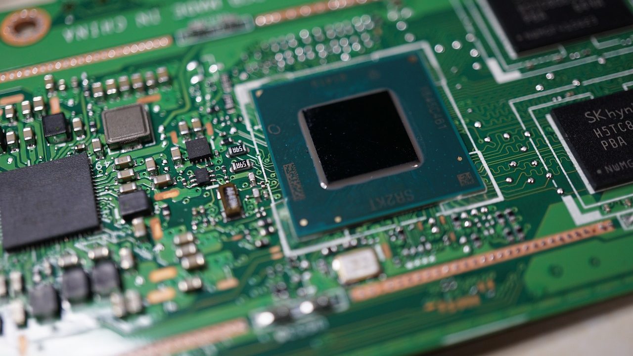 A close-up of a green circuit board with gold-plated connectors and microchips.