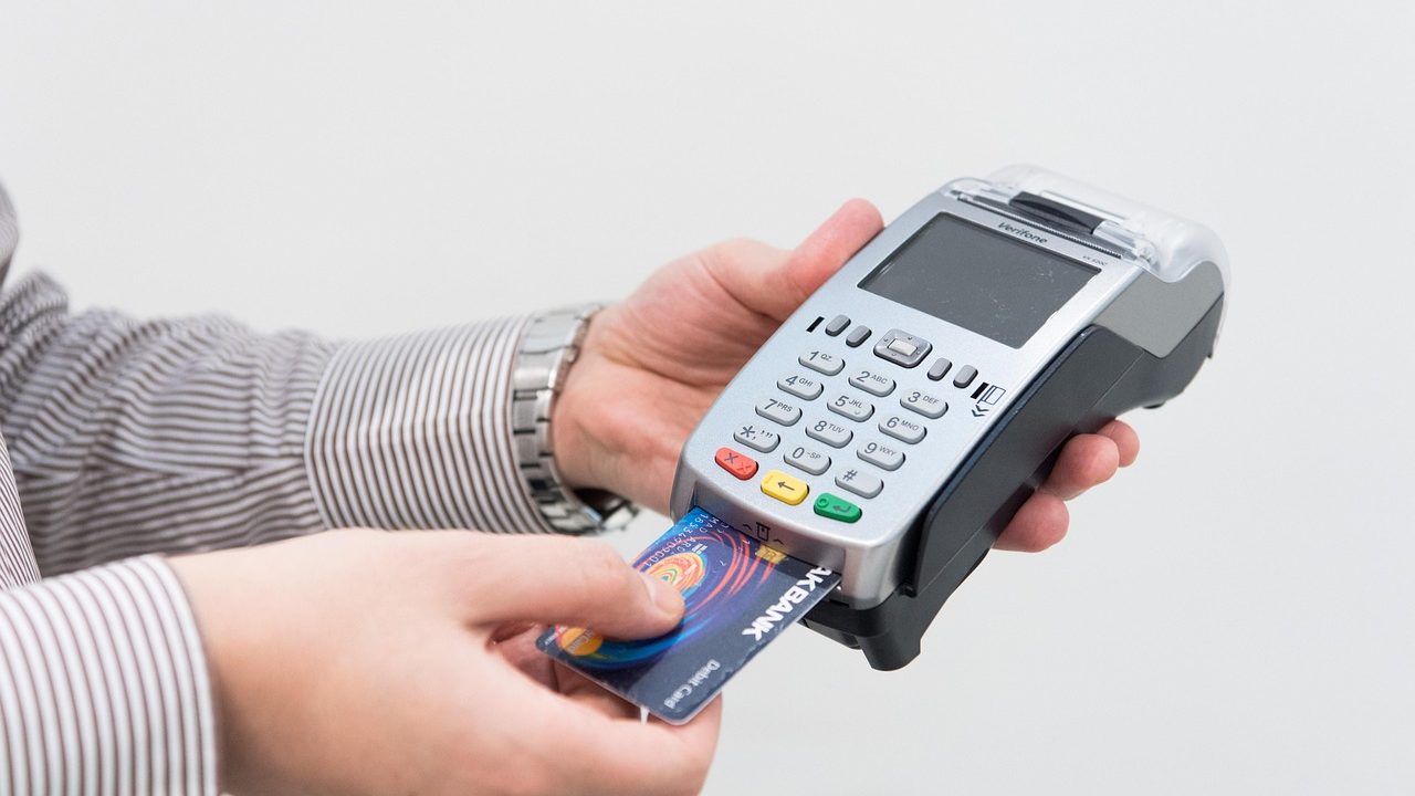 A contactless credit card being tapped on a retail payment terminal.