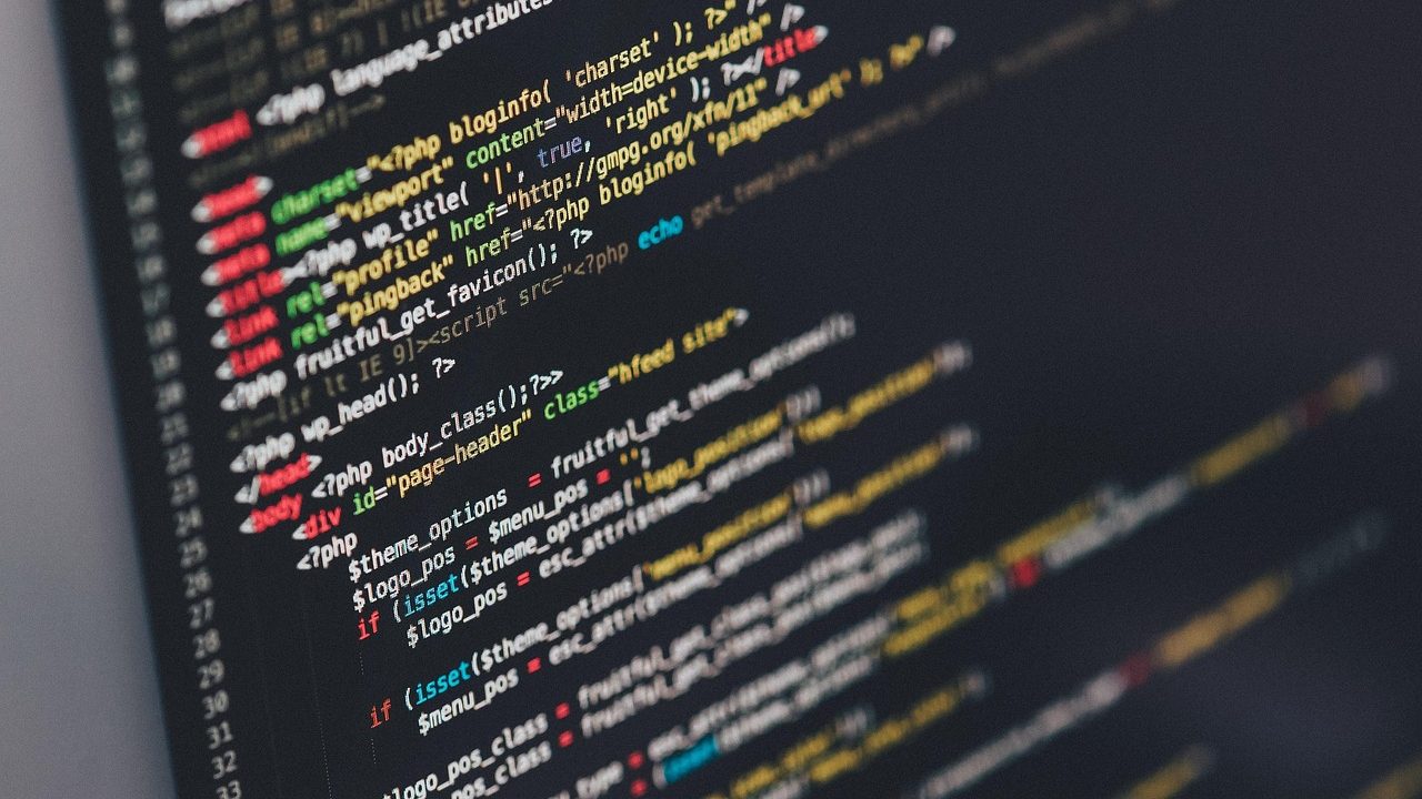 A developer's laptop displaying lines of terminal code in a darkened workspace.