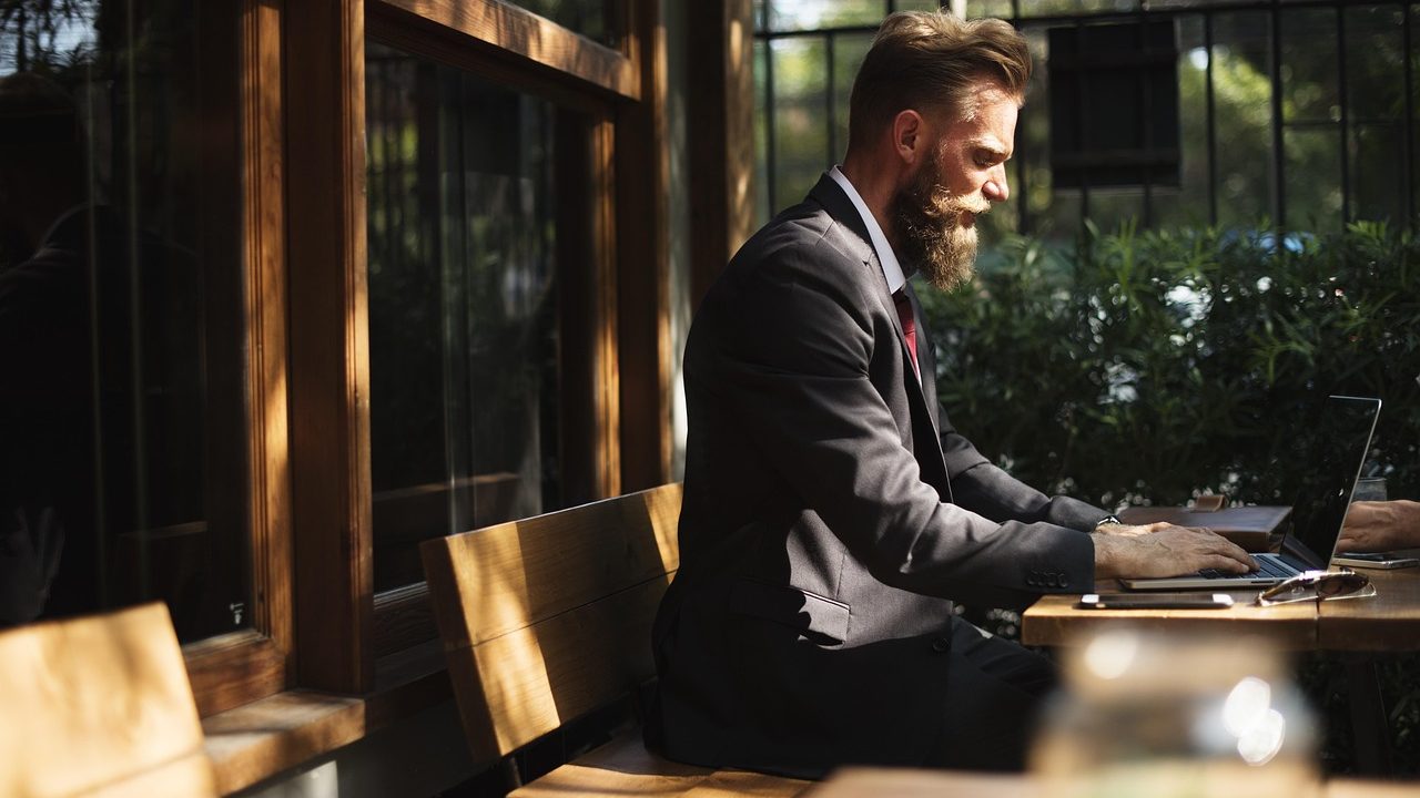 An open laptop on a cafe table with a coffee cup nearby.