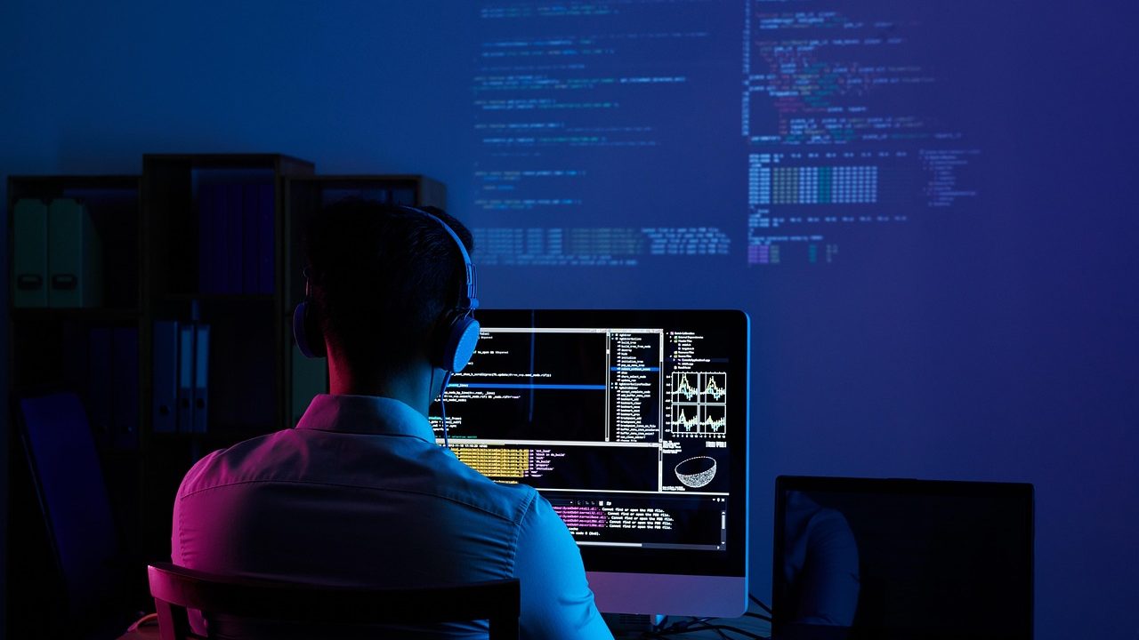 A programmer's monitor displaying colorful lines of code in a dark editor theme.