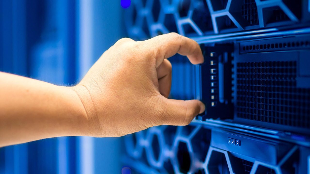Rows of illuminated server racks inside a dark data center facility.