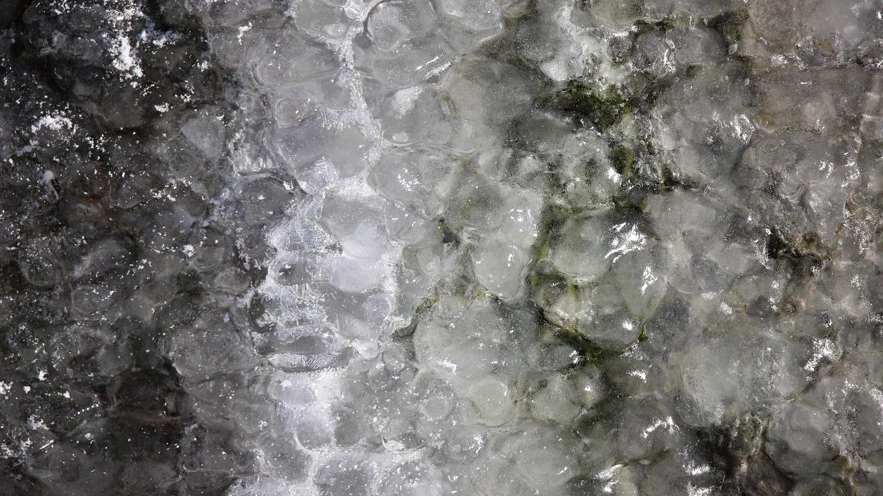 An artistic rendering of a cracked icy moon surface with a gas giant visible in the dark sky above.