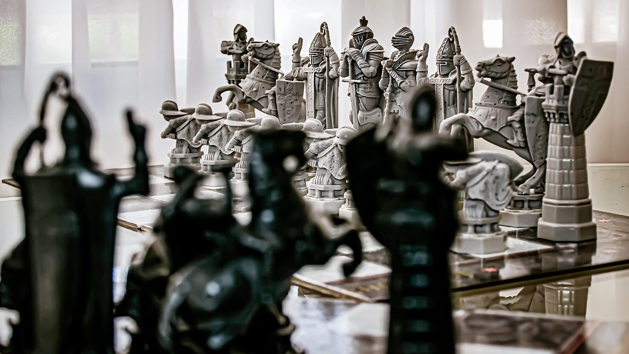 Chess pieces arranged on a wooden board, focused on the king and surrounding pieces.