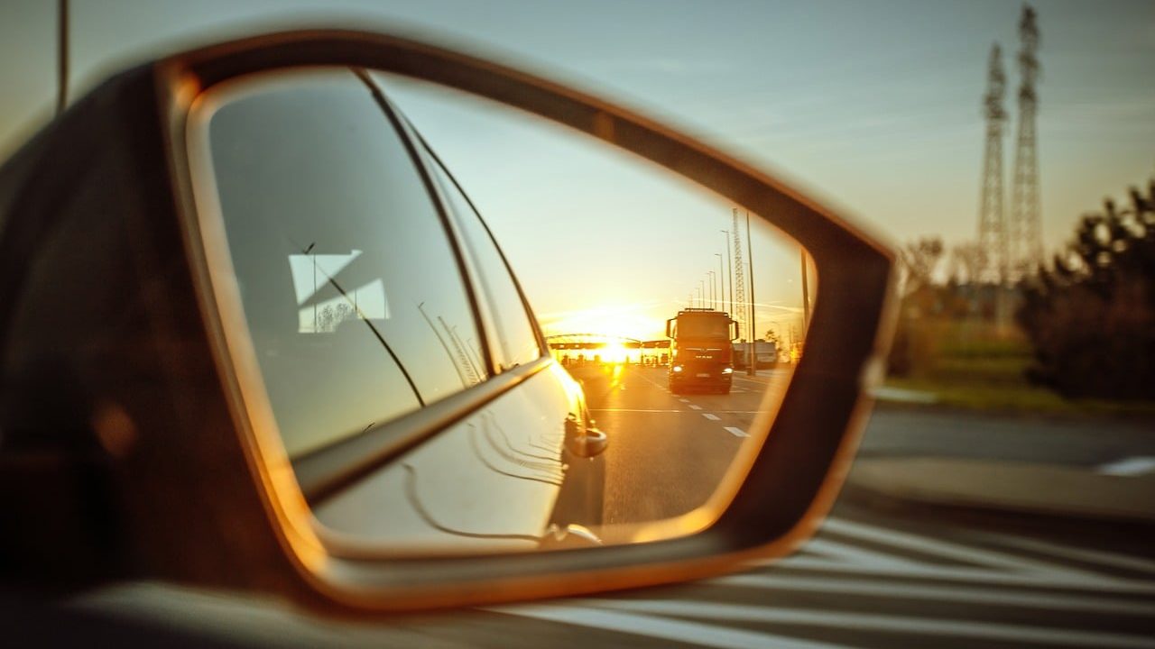 A self-driving vehicle with visible sensor arrays traveling on a multi-lane highway.