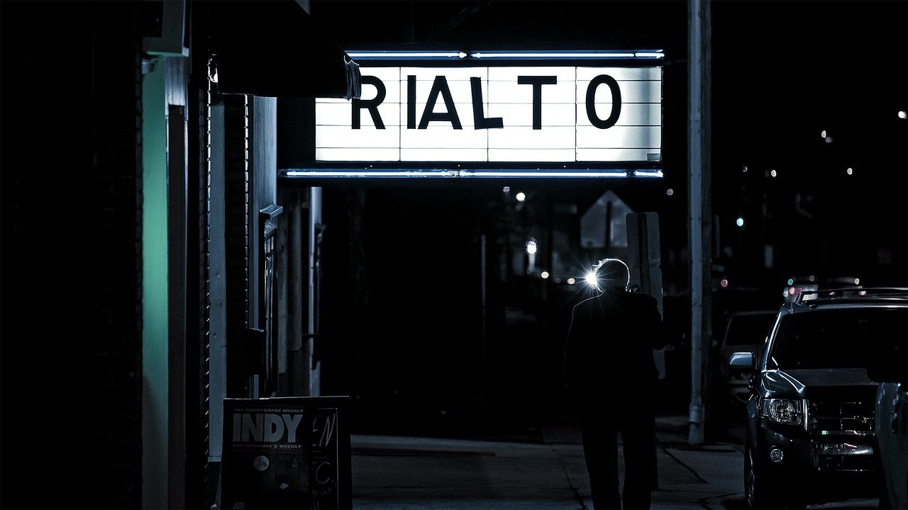 A lit movie theater marquee displays film titles at night.