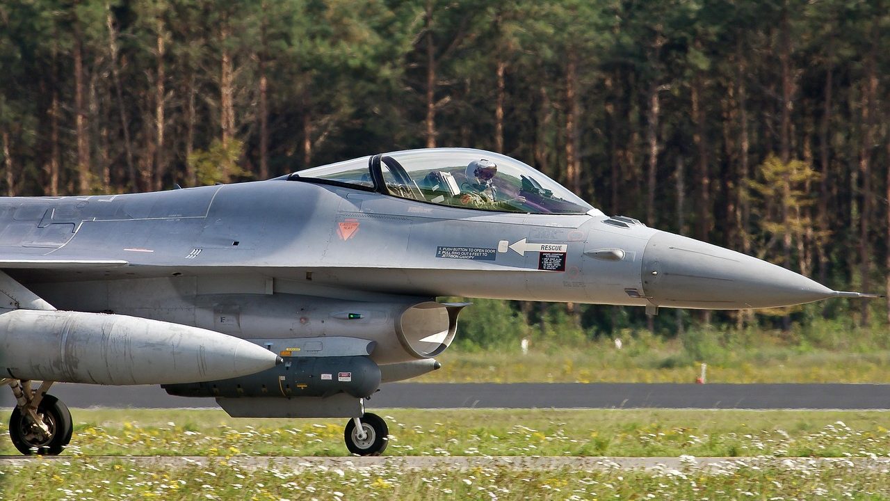A military aircraft sits on a tarmac runway under open sky.