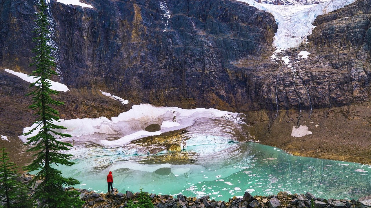 A retreating mountain glacier with exposed rocky terrain and meltwater pools in an alpine valley.