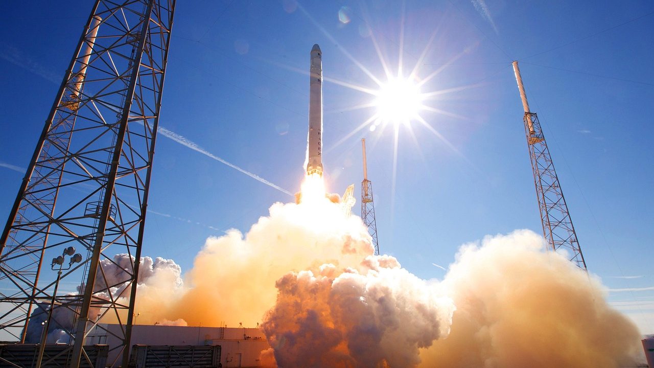 A large rocket on a launch pad surrounded by steam and flame at liftoff.
