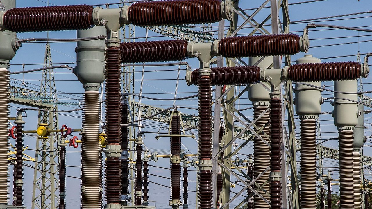 High-voltage electrical transformers and power lines at a substation at dusk.