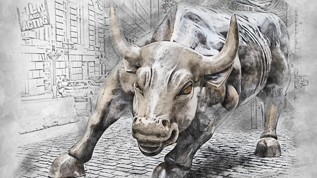 The iconic bronze bull statue stands on a city street in a financial district.