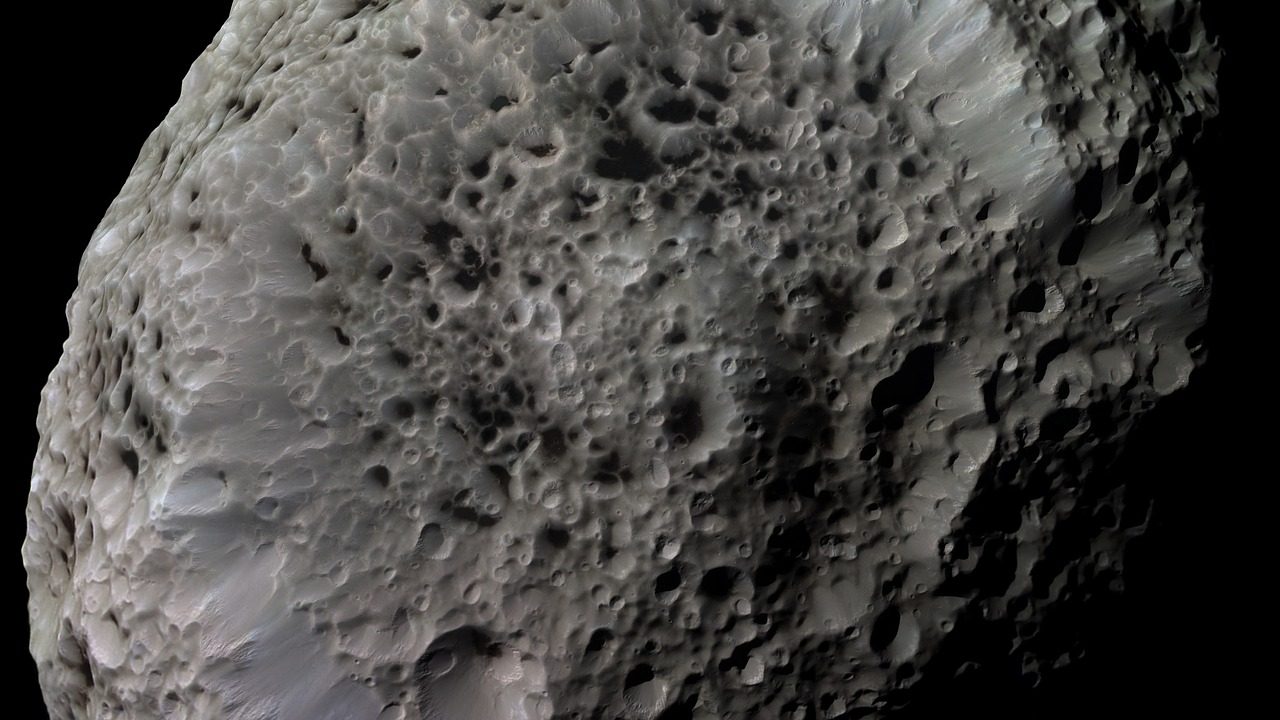 Aerial view of a large circular impact crater surrounded by rocky terrain and sediment layers.