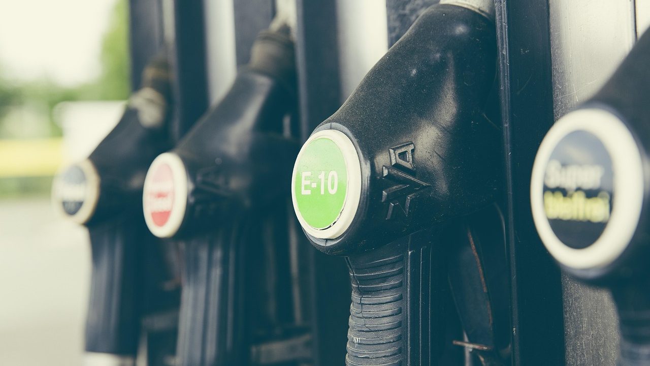 A row of fuel pumps at a gas station displaying prices on illuminated digital displays.