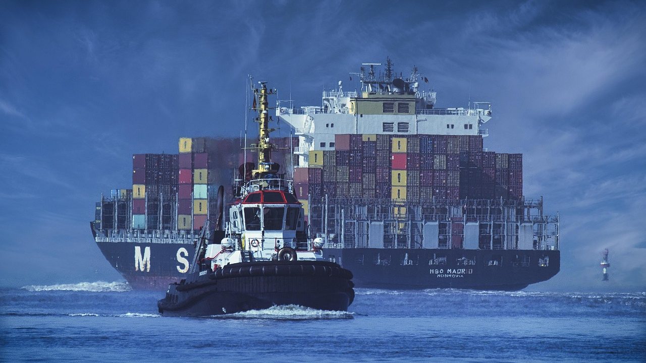 A large cargo vessel sailing alone on a calm open sea under grey skies.