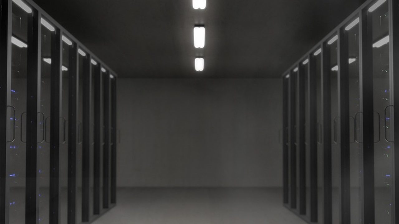 Rows of illuminated server racks inside a data center bathed in blue light.