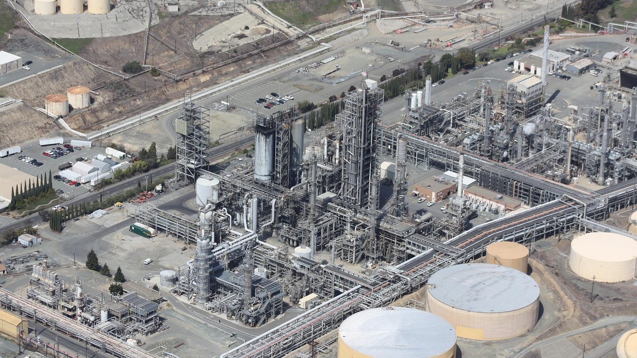 Large industrial pipelines running across flat terrain under a wide open sky.
