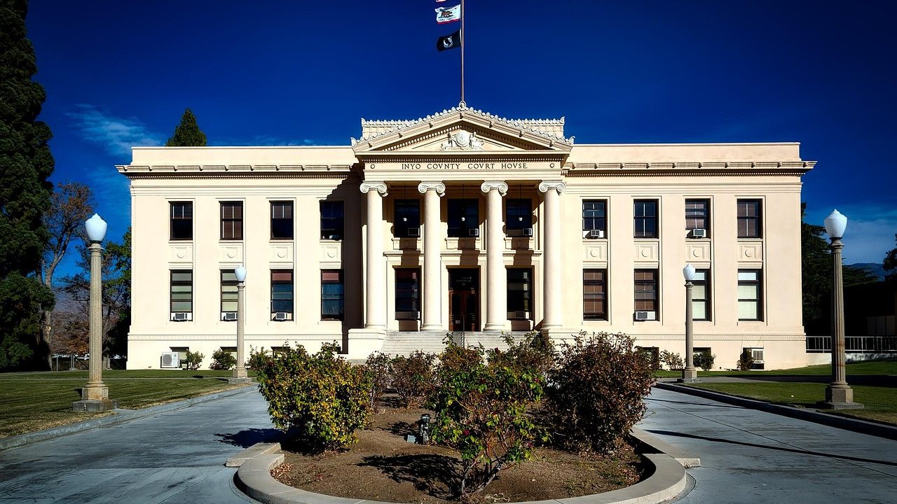Stone columns at the entrance of a courthouse building photographed from a low upward angle in daylight.