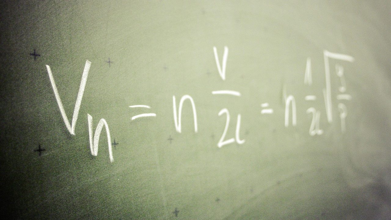 Complex mathematical equations and formulas written across a large chalkboard.
