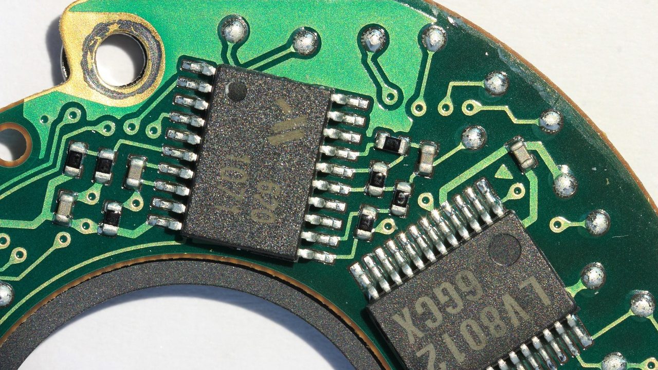 Extreme close-up of green circuit board showing intricate copper traces and components.