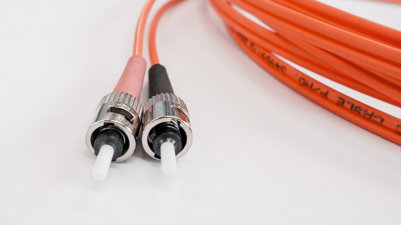 Glowing strands of fiber optic cable carrying pulses of light against a dark background.