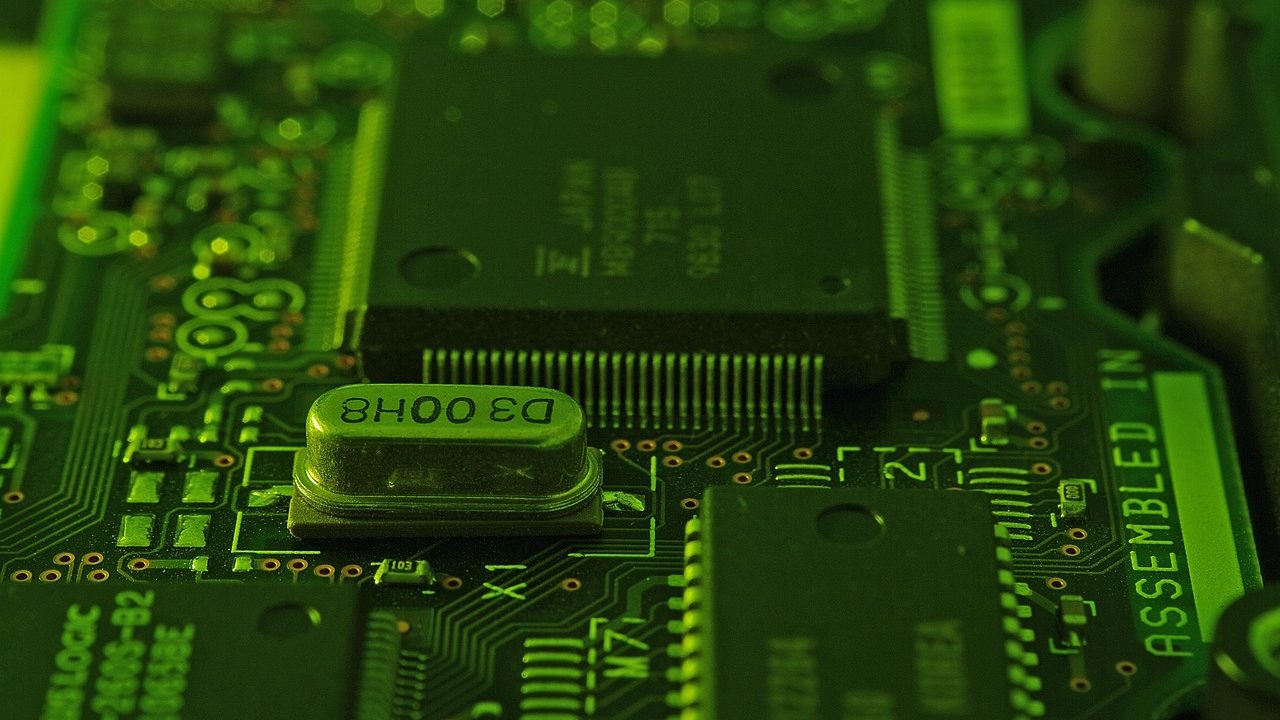 Extreme close-up of a green circuit board showing copper traces and microchip components.