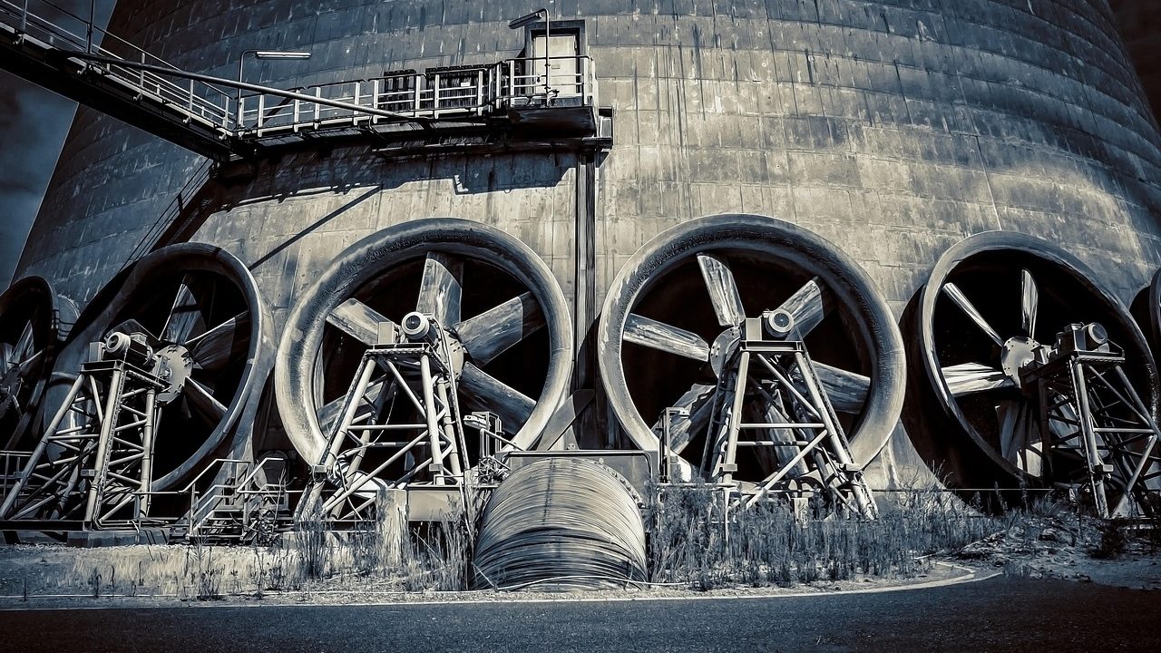 Large industrial cooling towers releasing steam against a clear blue sky.