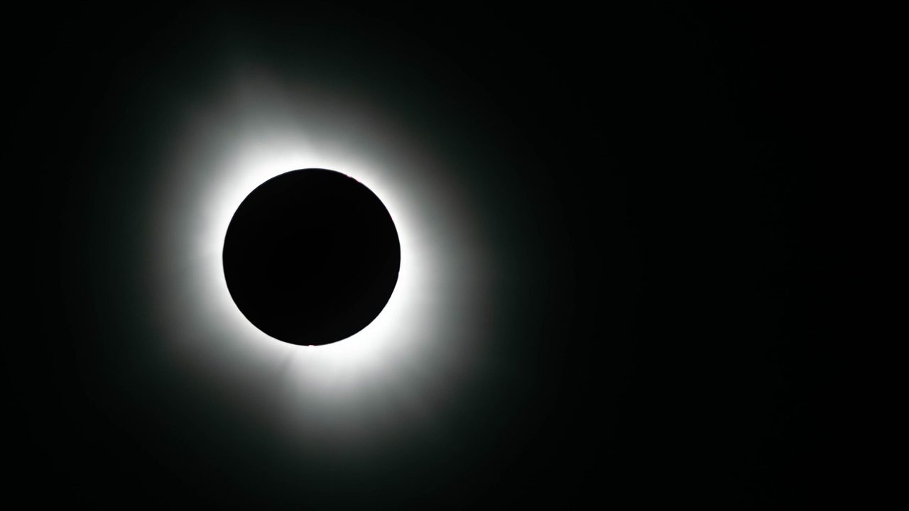 The sun's corona glows around the dark silhouette of the moon during a total solar eclipse.