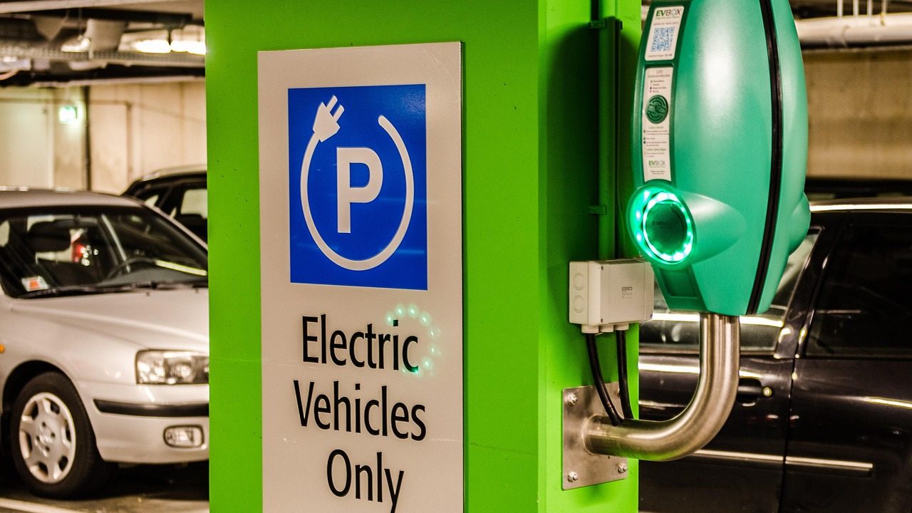 An electric vehicle plugged into a charging station in a parking area.