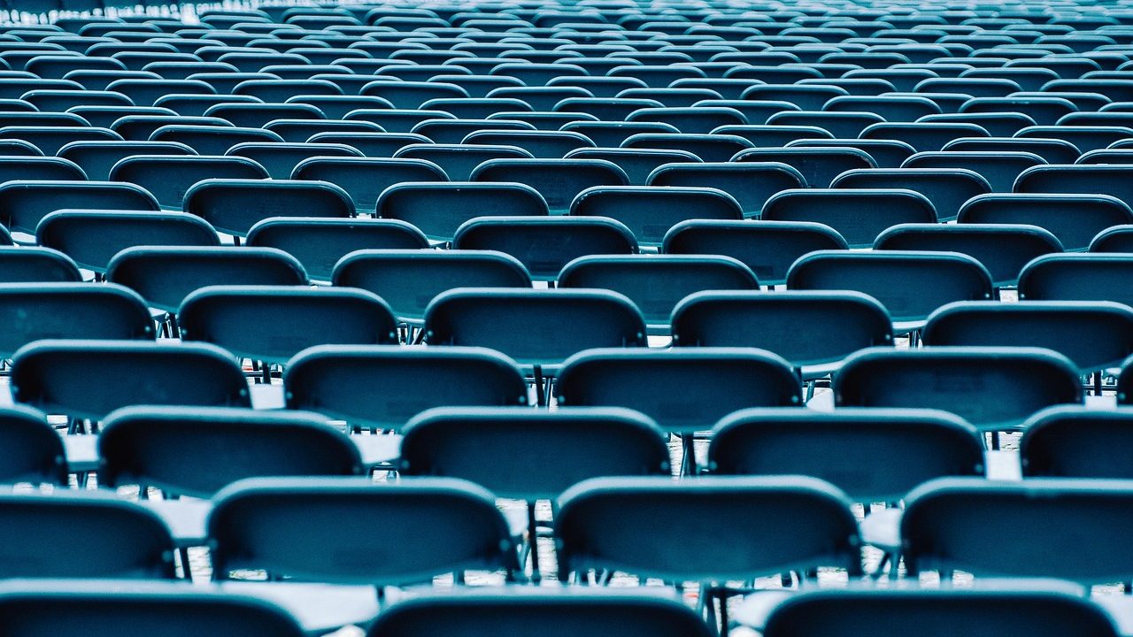 Rows of curved delegate desks fill a large domed assembly hall lit by overhead lights.