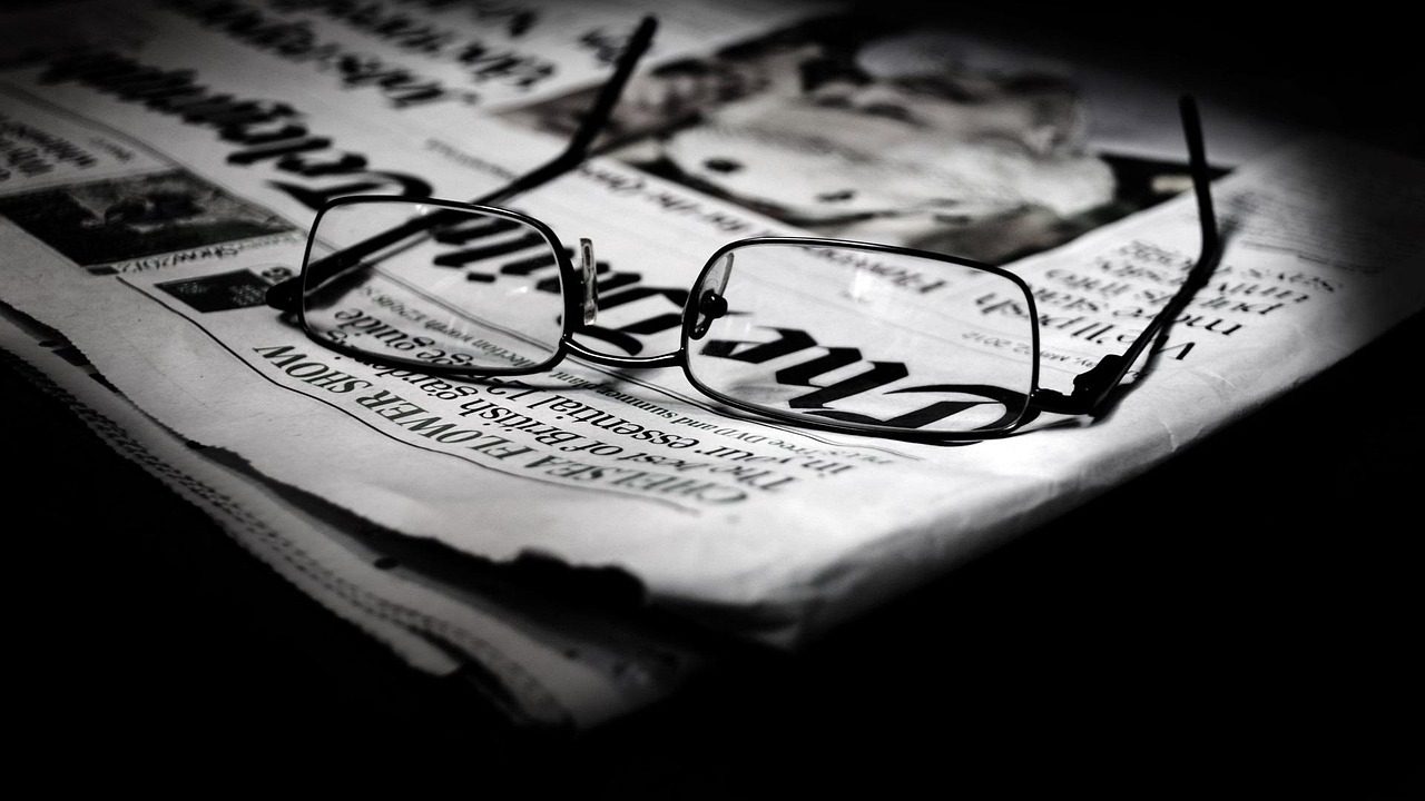 Rows of newspapers rolling off a commercial printing press in a production facility.